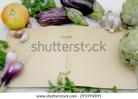 Recipe book open kitchen in a blank page surrounded by vegetables