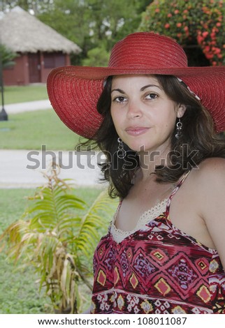 Beautiful Latino woman in summer fashion with a wide brimmed red straw hat and pretty patterned dress