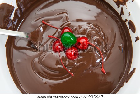 Chocolate and Cherries. Close up of melted chocolate in a white pot. Delicious and popular sweet staple. Texture and highlights in one of the most popular sweet food.