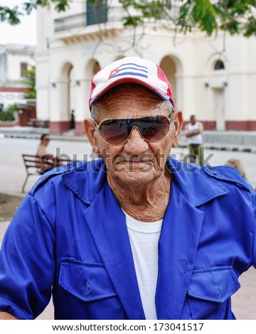 SANTA CLARA -JANUARY 8, 2013: Old guy wearing a cap with the Cuban flag on it. Typical uniform of the street sweepers. Seen in Santa Clara, Cuba on January 8, 2013