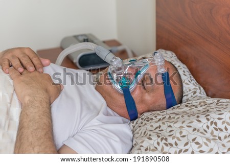 Man suffering from sleep apnea sleeping wearing the CPAP mask.