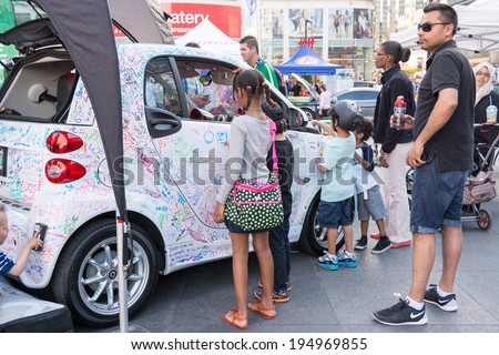 TORONTO,CANADA-MAY 24, 2014: Smart cars marketing its electric cars to children in Dundas Square. Smart Automobile is a division of Daimler AG that designs, manufactures and markets microcars.