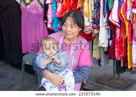 TORONTO, CANADA - OCTOBER 11, 2014: Retail worker and child in China town which s an ethnic enclave with a high concentration of ethnic Chinese residents and businesses in Dundas St. W and Spadina Ave
