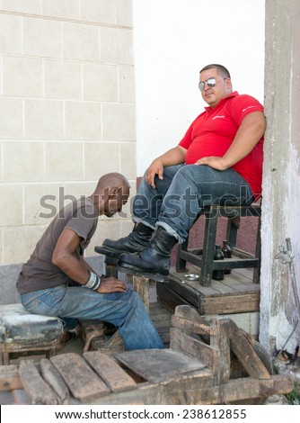 TRINIDAD,CUBA-JULY 22,2014: Shoe shiner or shoe shine person working. After the economic reforms of Raul Castro, Cubans can be self employed and make a living apart from the government.