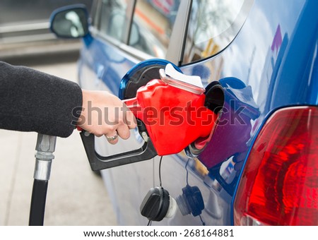 Filling the tank of a car in a gas station. Woman fills the tank of her beautiful blue efficient car at a pump in a gas station in Toronto