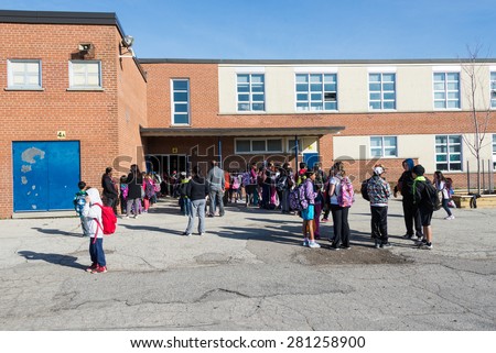 TORONTO,CANADA-MAY 22,2015: Everyday scene outside a public middle school: Parents and students waiting in line to enter building on first day of school, some students crowd together