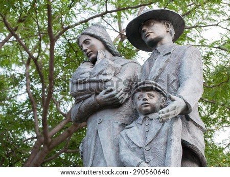 TORONTO,CANADA-JULY 21,2014: Monument to Italian-Canadian Immigrants: A statue of a family of four against tree background. The monument is a landmark to the Italian community in the city