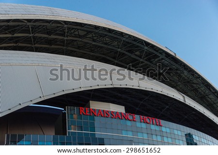 TORONTO,CANADA-JUNE 22,2015: Renaissance Hotel exterior and Rogers Centre roof.  A steel arch swoops over the glass windows and the red neon sign bearing the name of the hotel.