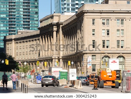 TORONTO,CANADA-JUNE 25,2015: Facade of Union Station, Toronto.  It is a brown stone building, with glass and steel skyscrapers behind.  Construction, traffic are visible in front of the station.