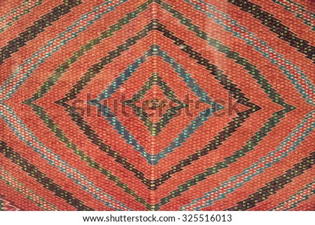 Full frame shot of Mexican native art pattern on a cloth. The art has zig-zag lines forming squares with in squares on an orange background. The Textiles of Mexico have a long history.