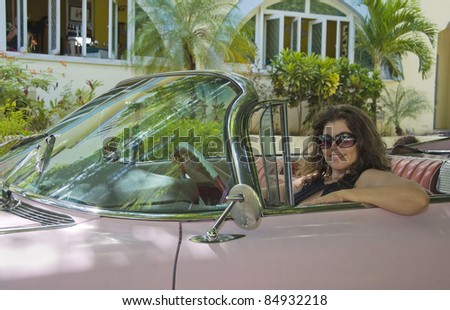 A woman drives a car from the 1950s