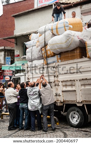 ISTANBUL, TURKEY - SEPTEMBER 21: A troop of street porters in Istanbul help to secure the cargo onto a lorry, on September 21,2012 in Istanbul.