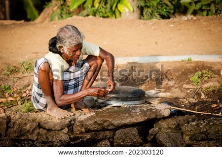 ALAPPUZHA, INDIA - January 23, 2014: An elderly woman fishing on banks of backwaters fishing on January 23, 2014 in Alappuzha, Kerela, India.