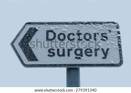 A direction sign to a doctor\'s surgery covered in frost and snow.