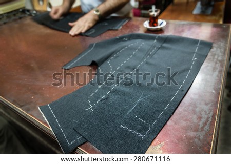 A tailor\'s work table with  cloth for a jacket cut and marked up for sewing. (SELECTIVE FOCUS)