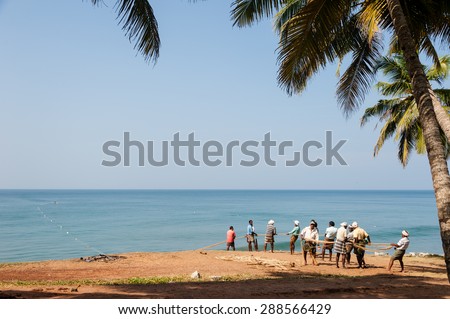 VARKALA, INDIA - JANUARY 19: Fishermen pulling a large fishing net in combined work out of the Arabian sea on January 19, 2014 in Varkala, Kerala, South India