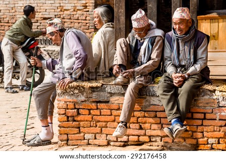 BHAKTAPUR, NEPAL - FEBRUARY 14,  2015: A group of elderly seniors sit and talk at a street corner in the ancient capital Bhaktapur in Nepal.