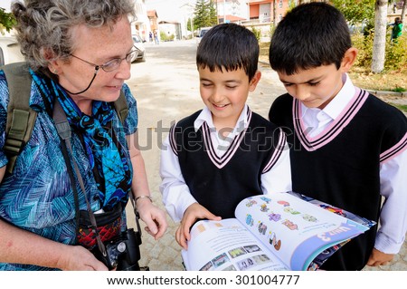 ISPARTA, TURKEY - OCTOBER 19, 2009: Two schoolboys practice their English with a tourist outisde a school in rural Turkey.