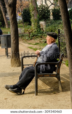 BARCELONA, SPAIN - MARCH 03, 2012: An old man resting on a park bench in Barcelona, Spain.