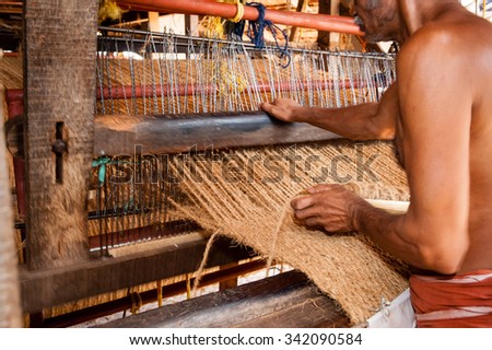 ALAPPUZHA, INDIA - JANUARY 22, 2014: Men working with a hand  operated coir loom to produce  matting at a co-operative in south India.