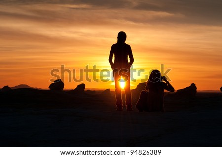 Two young females watch the sun setting in the White Desert in Egypt.