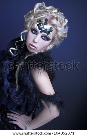 Stylish blond woman in dark dress with furs and with artistic visage