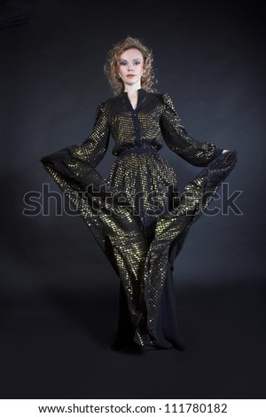 Dancer. Young woman waving dark dress with golden sparkles.