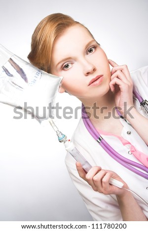Nurse. Portrait of young woman in doctor's smock and with medicine dropper.