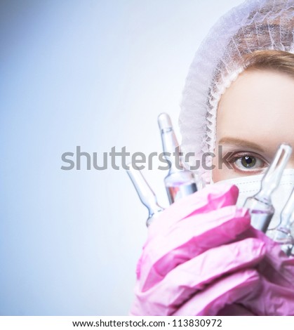 The doctor. Portrait of young woman in doctor\'s mask and with ampule\'s.