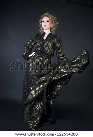 Dancer. Young woman in dark dress with golden sparkles.
