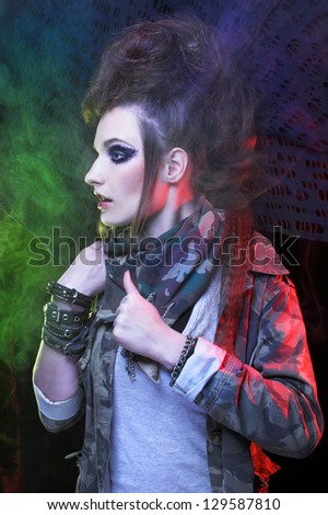Punk. Young woman with smokey eyes and with artistic hairstyle posing with smoke