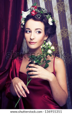 Portrait of young lady in red dress with flowers in her hair.
