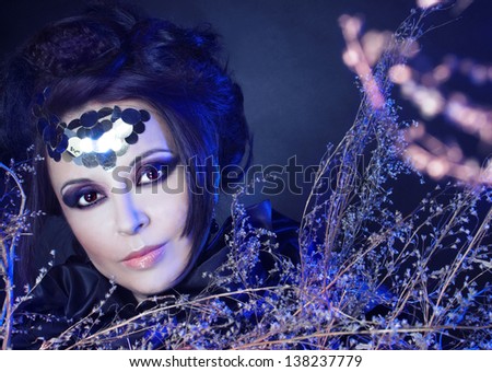 Creative lady. Portrait of stylish woman  with smokey eyes and spangles and with dry twigs