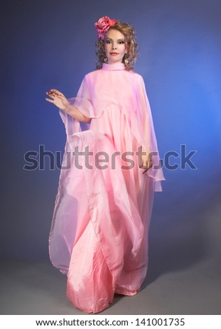 Dance. Charming woman in pink vintage dress and with flowers in hair.