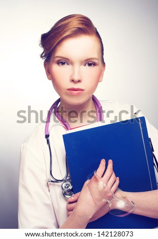 Portrait of young woman in doctor\'s smock and with documents