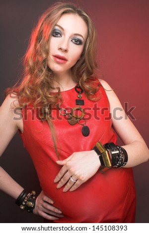 Very stylish pregnant woman with blong curly hair in rock star image