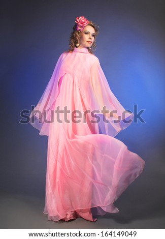 Dance. Charming woman in pink vintage dress and with flowers in hair.