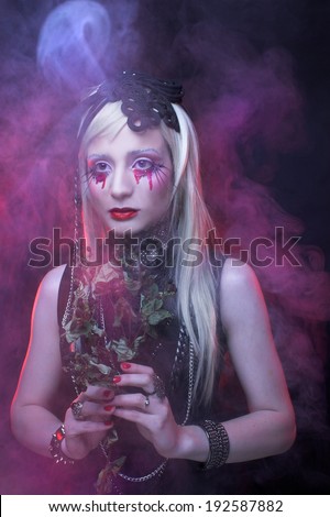 Young woman in black dress and with bloody tears.