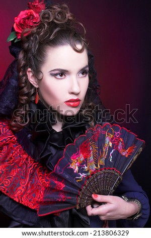 Spanish lady. Portrait of young woman in artistic image posing with fan