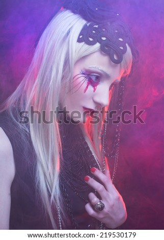 Halloween lady. Young woman in black dress and with bloody tears.