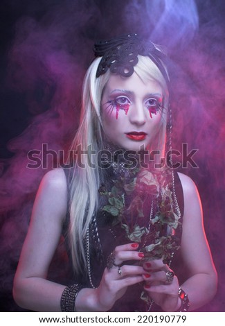 Halloween image. Young woman in black dress and with bloody tears.