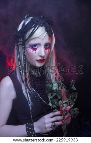 Halloween. Young woman in black dress and with bloody tears.