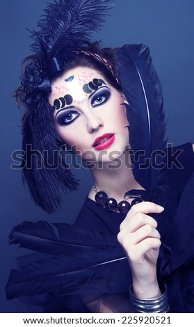 Halloween. Vintage lady in dark retro style and with feathers in her hair.