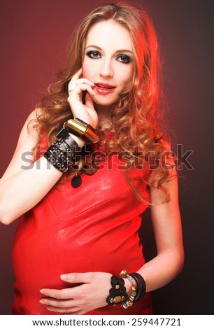 Very stylish pregnant woman with blond curly hair in rock star image