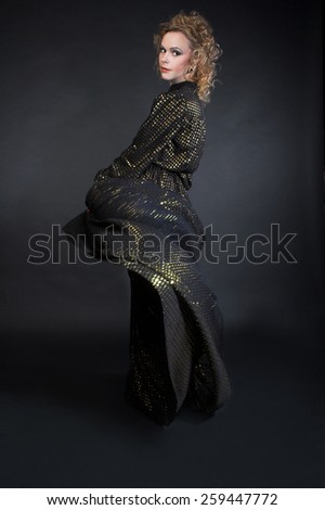 Dancer. Young woman in dark dress with golden sparkles.