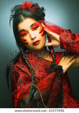 Portrait of young woman in black and red silk  with creative make-up