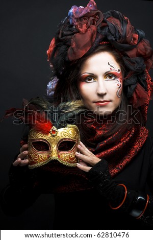 Young woman in black and red silk with mask in her hands
