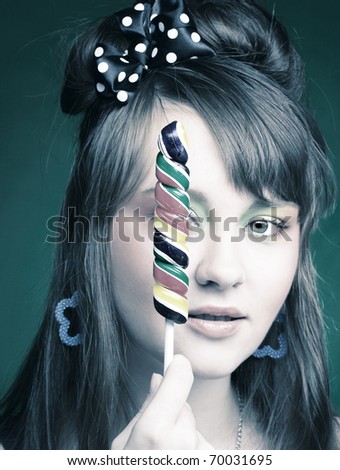 Portrait of young brunette with creative make-up and with lollipop in her hands.