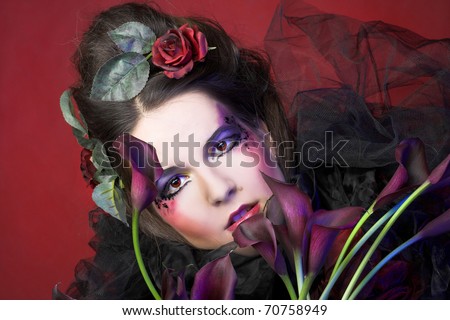 Romantic portrait oj young woman in creative image abd with dark flowers in her hands