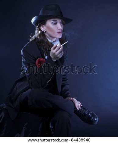 Androgynous. Portrait of young woman in men\'s suit smoking cigarette.